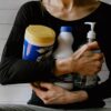 woman in black long sleeve shirt holding white and yellow plastic bottle