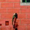 person in brown leather jacket standing in front of brown brick wall